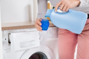 Close up Of Female Hands Pouring Laundry Detergent In The Blue Bottle Cap