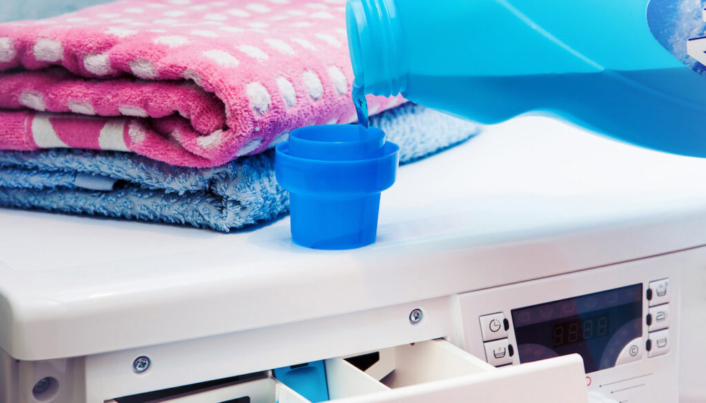 When to Skip Fabric Softener...and What to Use Instead | Laundry Care person putting liquid fabric softener in a washing machine dispenser