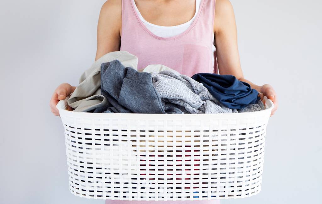 close up of woman holding a white basket full of laundry