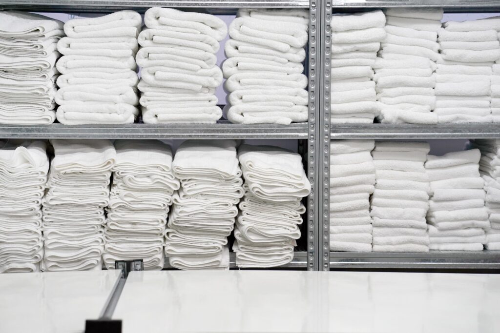 Clean, folded commercial laundry items including whiten towels and linens.