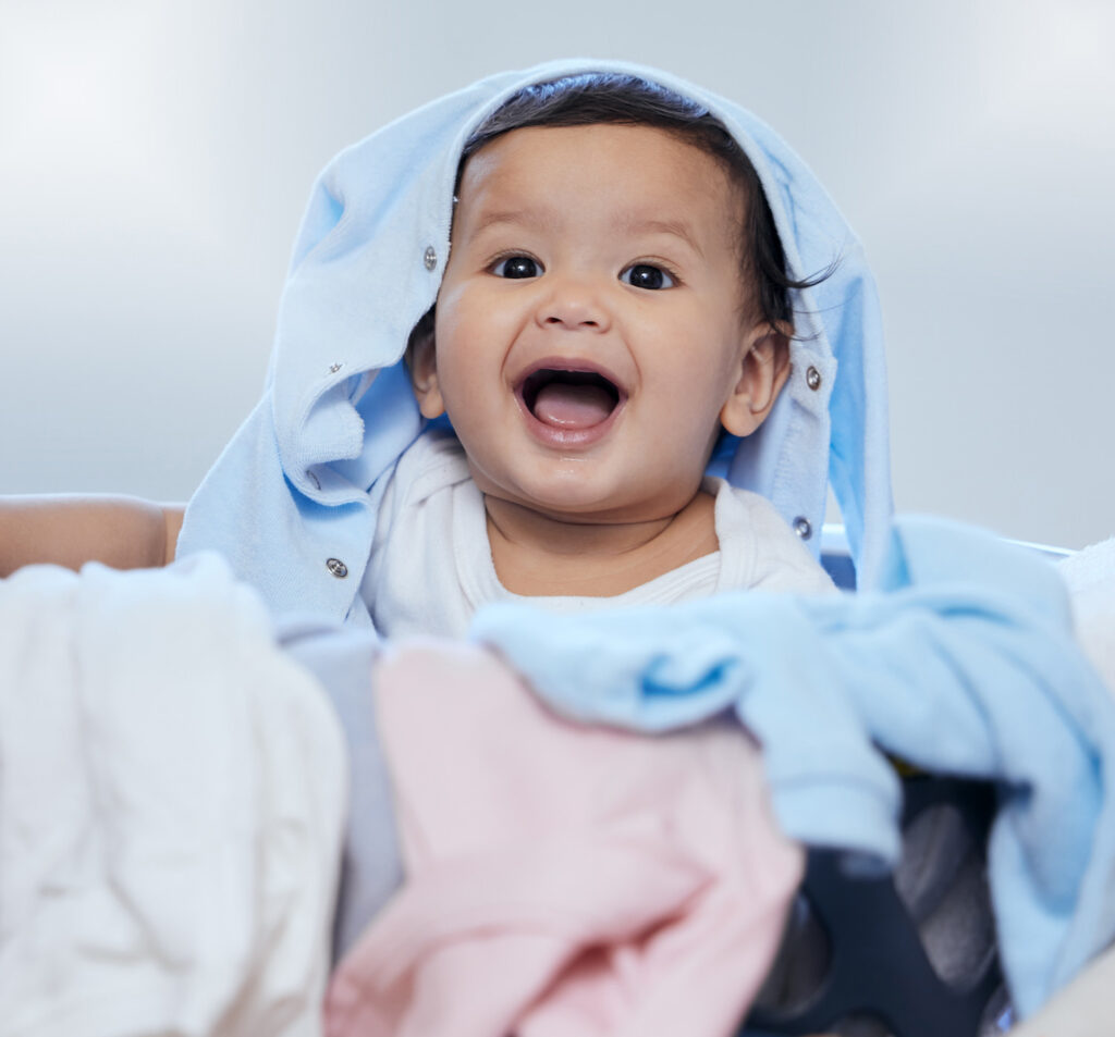 happy baby playing in basket of clean laundry