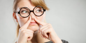 Woman holding her nose to avoid smelling smoke odor