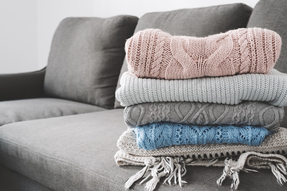 a stack of sweaters on a couch